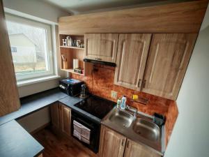 a small kitchen with wooden cabinets and a sink at GUNER Apartament Bełchatów in Bełchatów