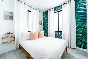 a white bedroom with a large bed and windows at Tropical Getaway in Aguadilla