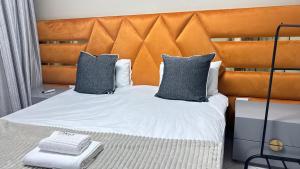 a bed with an orange headboard and two pillows at Mercy Guesthouse in Thohoyandou