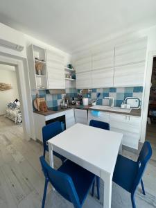 a kitchen with a white table and blue chairs at Aquarium - Villa con accesso al mare - parcheggio in San Vito