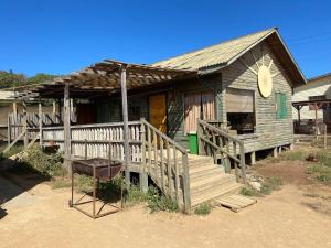 a wooden house with a porch and a grill outside at Cabaña a pasos del mar in El Cerrillo