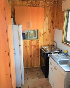 a kitchen with wooden cabinets and a white refrigerator at Cabaña a pasos del mar in El Cerrillo