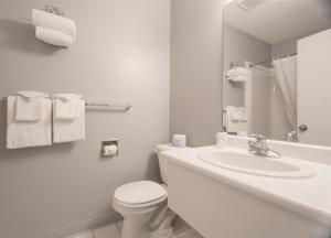 a white bathroom with a toilet and a sink at Mountain View Inn in Canmore +52 photos