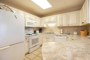 a kitchen with white cabinets and a white refrigerator at Phoenix VI 61204 in Orange Beach