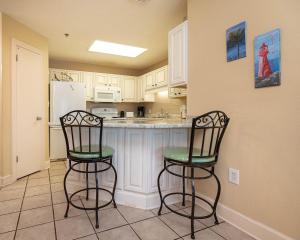 a kitchen with two bar stools and a refrigerator at Phoenix VI 61204 in Orange Beach