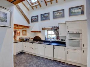 a large kitchen with white cabinets and a window at 4 Bed in Llandudno Junction oc-58301 in Llandudno Junction