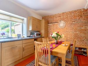 a kitchen with a wooden table and a brick wall at 2 Bed in Holt oc-ncc66 in Blakeney