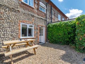 a wooden bench in front of a brick building at 2 Bed in Holt oc-ncc66 in Blakeney