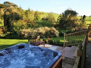 a hot tub in a yard with a bench at 3 Bed in Dunsyre oc-lk15m in Walston