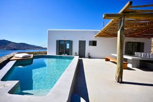 a villa with a swimming pool in front of a house at Sunwave Mykonos Villa in Mykonos