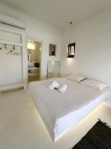 a white bedroom with a bed with two towels on it at Sunwave Mykonos Villa in Mykonos +13 photos