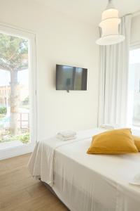 a white bedroom with a bed and a tv on the wall at Room45 in Marzamemi