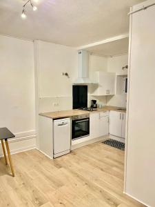 a kitchen with white cabinets and a wooden floor at Charmant 3 pièces in Saint-Claude