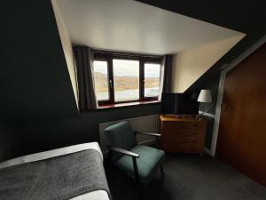 a bedroom with a bed and a chair and a window at Dunan Hotel in Breasclete