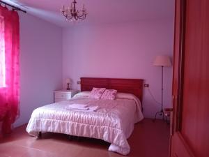 a bedroom with a bed with pink walls and a chandelier at Uliveto in Sulzano