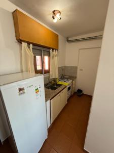 a kitchen with a white refrigerator and a sink at Departamentos Li-Del in Monte Hermoso +4 photos