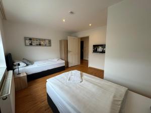a room with two beds and a tv in it at Pension Linderhof Augsburg in Augsburg