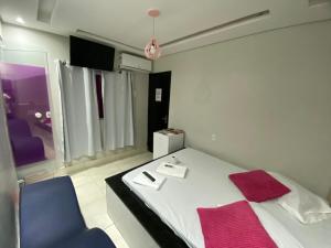 a bedroom with a white bed and a blue chair at Hotel Suíte in Brasília