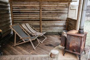 a rocking chair and a wood stove on a porch at Sky Cabin. Cosy Forest Log Cabin 3 night minimum in Wareham