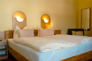 a bedroom with a large white bed with two lights on the wall at Hotel-Pension Lender in Bad Freienwalde +25 photos