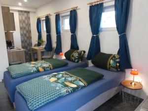 two beds in a room with blue curtains at Privates Studio mit Parkplatz NAC in Euskirchen