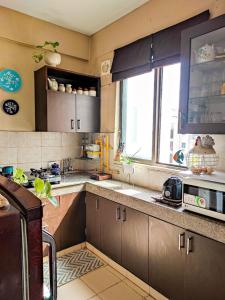 a kitchen with brown cabinets and a window at Seaswan resort in Alibaug