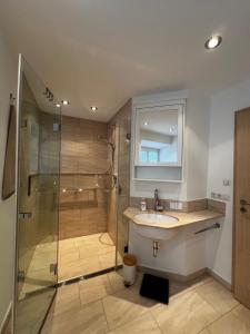 a bathroom with a shower and a sink and a mirror at Ferienwohnung Rössler in Brannenburg