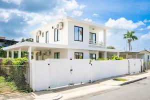a white house behind a white fence at Tropical Getaway in Aguadilla