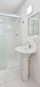 a white bathroom with a sink and a shower at Aloogar Caragua Beach in Caraguatatuba