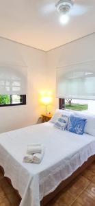 a bedroom with a large white bed with blue pillows at Aloogar Caragua Beach in Caraguatatuba