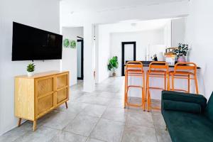a living room with a flat screen tv and orange bar stools at Tropical Getaway in Aguadilla