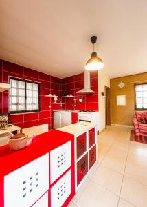 a red kitchen with white cabinets and red walls at Barbeito Country House in Paraíso +20 photos