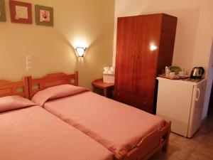 a bedroom with two beds and a cabinet and a refrigerator at Villa Mary Galini in Ireon +3 photos