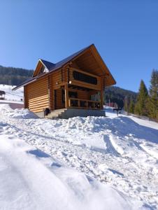 a log cabin in the snow with footprints in the snow at Шепіт Карпат 2 in Synevyrsʼka Polyana