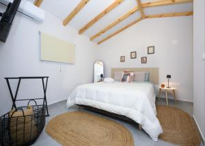 a white bedroom with a large bed and two rugs at La casa di Antonio Corfu in Alepou