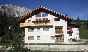 a white house with a balcony and mountains in the background at Ciasa Rudiferia Appartamenti in Alta Badia in Badia