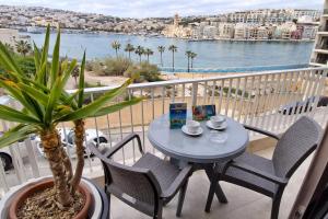 a table and chairs on a balcony with a view of the water at Seafront Apartment - Balcony over the Harbour in Marsaskala