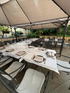 a table with white tables and chairs under an umbrella at Hotel Giardino del Sole in Savona