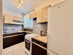a kitchen with wooden cabinets and a white refrigerator at Przy Zamenhofa in Nowa Sól