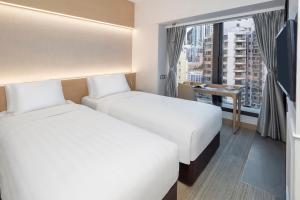 two beds in a hotel room with a window at Y Hotel Hong Kong in Hong Kong