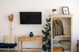 a living room with a table and a tv on a wall at Bright studio Martigny - 30 min from Verbier - free parking in Martigny-Ville