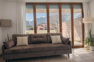 a couch in a living room with a large window at Bright studio Martigny - 30 min from Verbier - free parking in Martigny-Ville