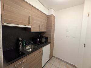 a small kitchen with a sink and a microwave at Bright studio Martigny - 30 min from Verbier - free parking in Martigny-Ville +5 photos