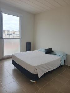 a bed in a room with a large window at Depto tranquilo y equipado cerca del mar in Puerto Madryn +5 photos