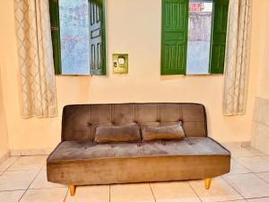 a brown couch sitting in a room with windows at Casa de Nara in Lençóis