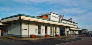 a white building with a green roof on a street at Chestnut Lodge Bed & Go in Eastleigh