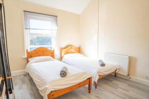 two twin beds in a room with a window at Chestnut Lodge Bed & Go in Eastleigh +4 photos