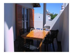 a wooden table on a balcony with chairs around it at Playa MaLú in Las Toninas