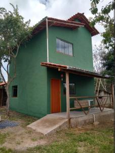 a green house with a red door at Chalé Jardim Mágico in Milho Verde +2 photos