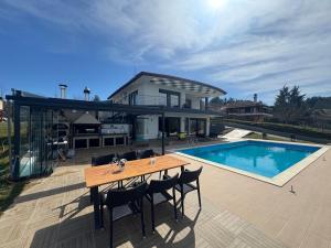 a house with a table and a swimming pool at Luxury Villa Rafaela Οικογενειακή βίλα με ιδιωτική πισίνα, BBQ κ παιχνίδια Ιδανική για οικογένειες με παιδια in Grevena